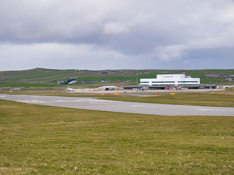On a cloudy, overcast day, a helicopter lands at Sumburgh Airport in the south of Shetland in the UK.