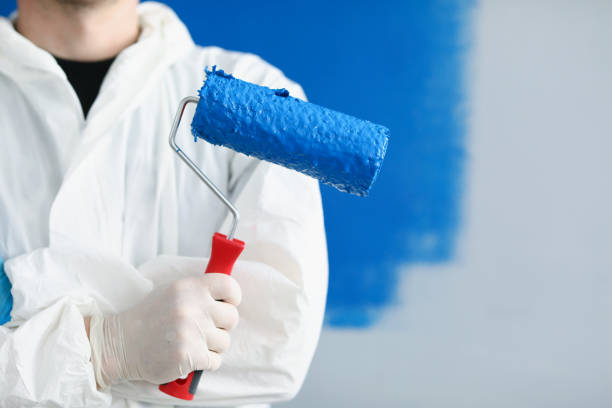 istock Man builder repairman holding roller with blue paint in his hands closeup 1322990298