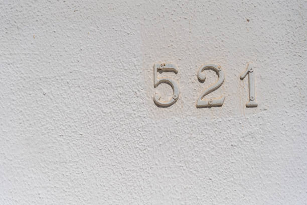 Metal house number 521 on a white stucco wall background