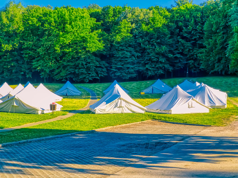 Group of White Tents on the Meadow in Nature Near the Forest.