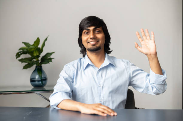istock Cheerful indian colleague waving hand into the camera 1322991979