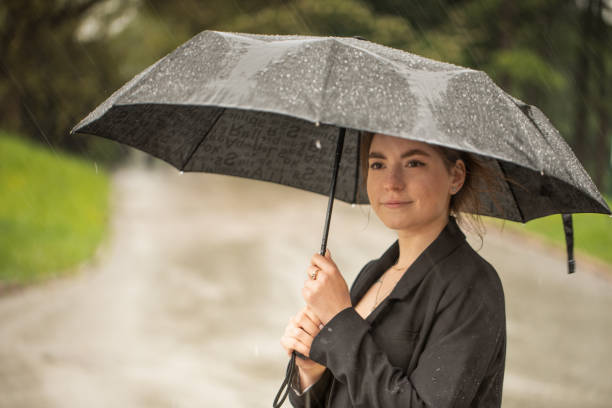 istock Girl under a black umbrella during the rain. 1322992108
