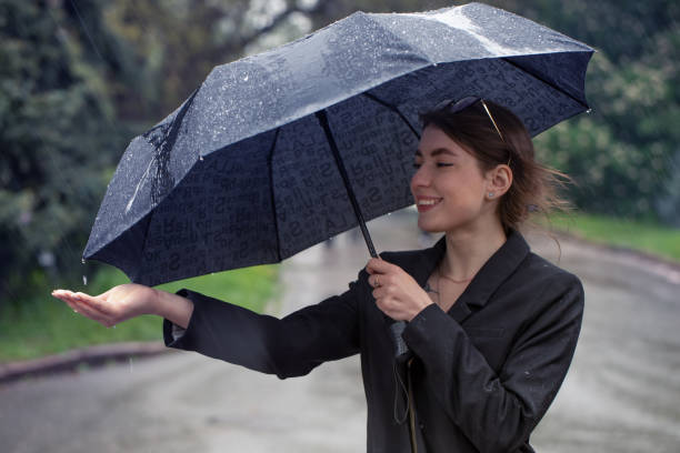 istock Attractive brunette under an umbrella catches raindrops. 1322992114