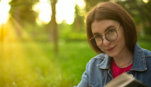 istock Girl in the park on a bench reading a book 1322992120