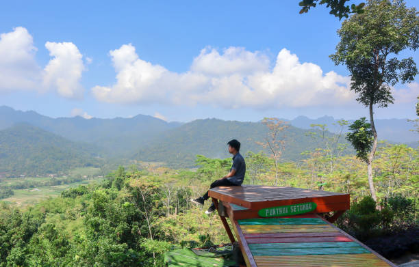 istock Man on a mountain peak with mountains view with a casual shirt 1322993334