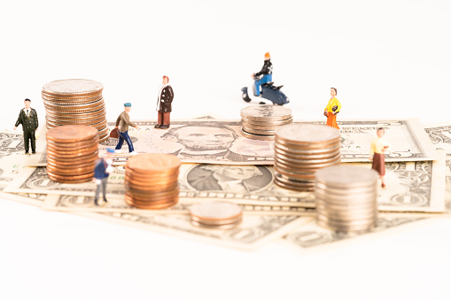 Miniature people, coins and banknotes over  white background