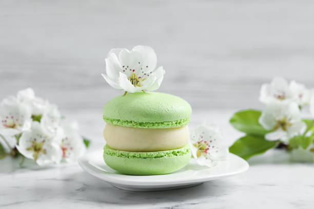 istock Green macaron and flowers on white marble table 1322996195