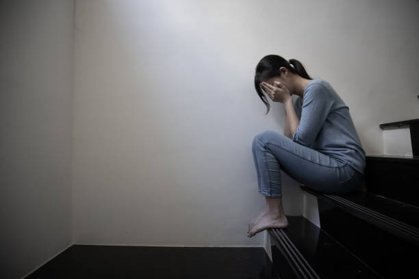 female bullied sit on staircase Asian female bullied - Young depressed and sad Chinese girl sitting lonely on staircase suffering bullying and harassment suicide photos stock pictures, royalty-free photos & images