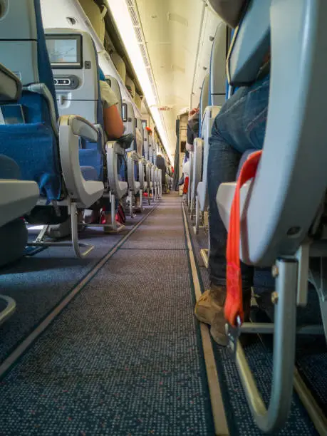 Aircraft cabin interior,aisle of airplane,back view of passenger seats with monitor screen.Aeroflot,Russian international flight in pandemic.Travel concept,selective focus.Open luggage compartments