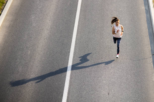 istock Young woman jogging on the road 1323002236