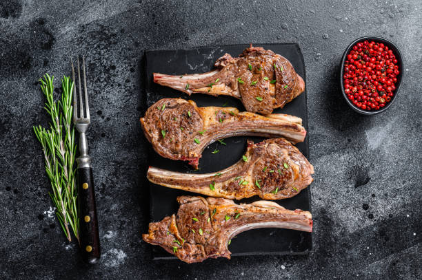 Barbecue fried lamb meat chops on a marble board. Black background. Top view Barbecue fried lamb meat chops on a marble board. Black background. Top view. rack of lamb stock pictures, royalty-free photos & images