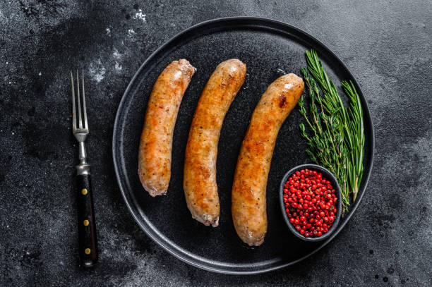 istock Sausages fried with spices and herbs on a plate. Top view. Black background 1323008045