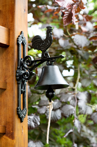 Outdoor interior with wooden fence and metal bell in the garden,