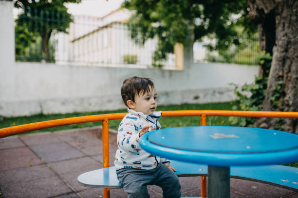 istock Cute Boy Sitting At Bench At Park 1323011964