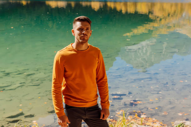 путешественник человек на хрустальном озере в осенних горах. горное озеро и путешественник - lake alaska mountain mountain range стоковые фото и изображения