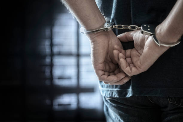 Criminal wearing handcuffs in prison Arrested man in handcuffs with handcuffed hands behind back in prison stealing crime stock pictures, royalty-free photos & images