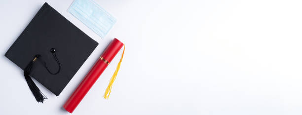 istock Graduation academic cap with diploma and mask isolated on white table background. 1323018778