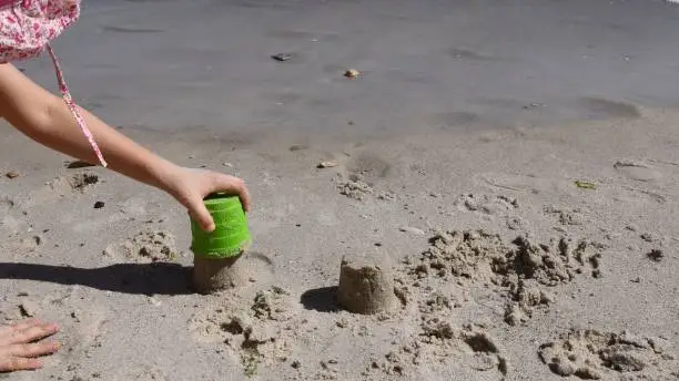 Photo of Child hand makes sandcastle with sand mold tool