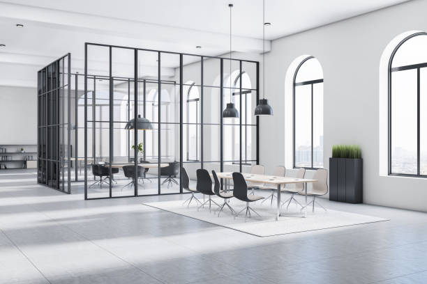 istock Sunny stylish open space office with monochrome style interior, big arched windows, light carpet on glossy floor and meeting room surrounded by glass transparent walls divided on black squares. 3D rendering. 1323020526