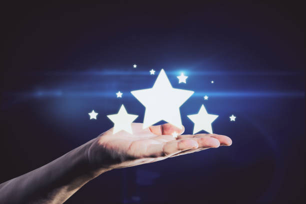 istock Hand holding glowing stars on blue background. Customer feedback and ranking concept 1323020594