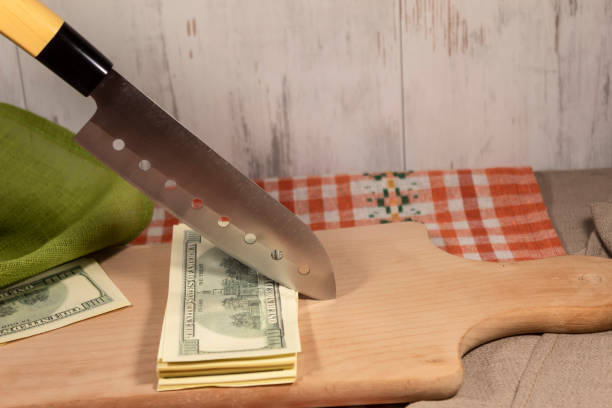 istock On a cutting board lies a bundle of notes, over which a knife blade hangs. 1323021433