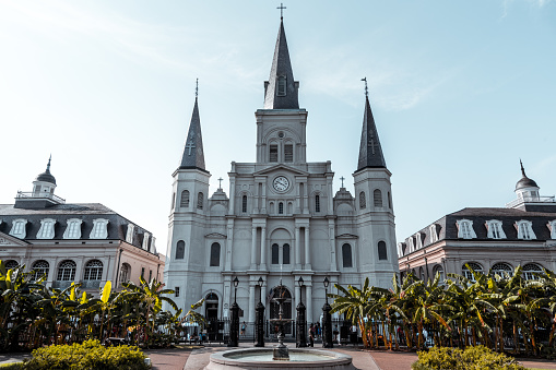 A beautiful sunny day in Jackson Square, New Orleans. St. Louis Cathedral and fountain plus tourists walking down the street.