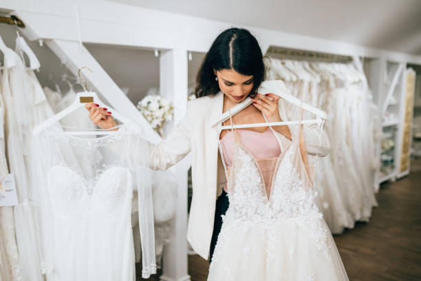 Bridal salon Attractive young blond woman is smiling and enjoying while choosing wedding dress in modern wedding salon. bridal boutique stock pictures, royalty-free photos & images