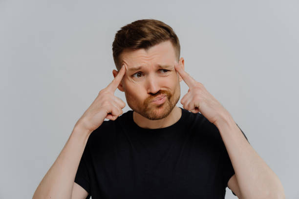 istock Concerned man holding fingers on temples and thinking 1323029019