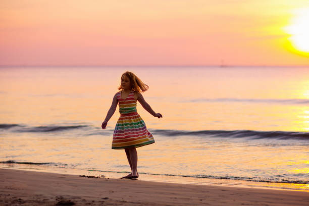 istock Child playing on ocean beach. Kid at sunset sea. 1323030231