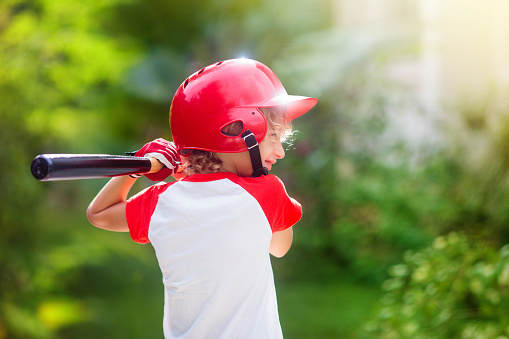 Kids play baseball. Child with bat and ball. Outdoor activity for healthy kids. Fun team ball game for boy and girl. Young athlete on baseball field. Little boy with helmet for safe exercise.