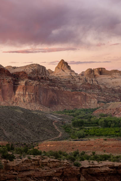 istock Trail Passes Through Valley of Apple Orchards Toward Rocky Formations 1323033025