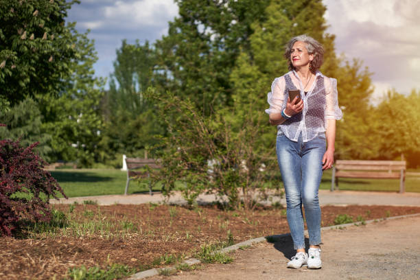 istock woman walking with her mobile phone, dressed in jeans 1323034111