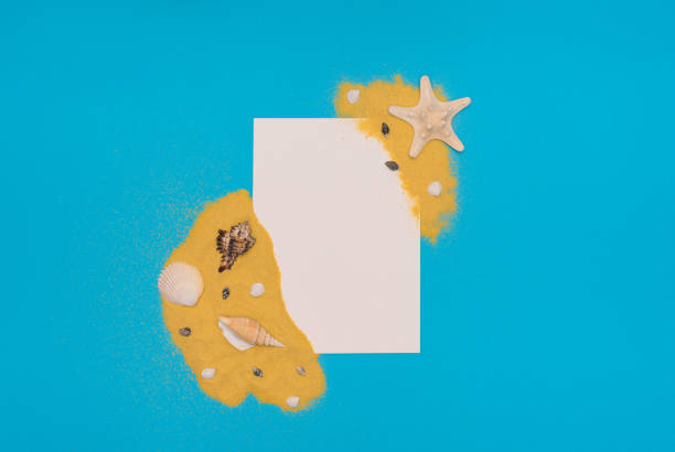 istock Different sea shells and starfish on bright yellow sand with white paper card note on blue background. Summer time concept. Flat lay style with copy space 1323036347