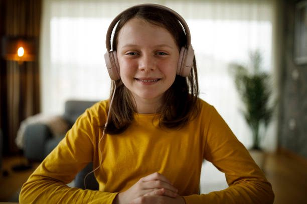 jeune fille souriante avec des écouteurs ayant un appel vidéo à la maison - speech talking teenager student photos et images de collection