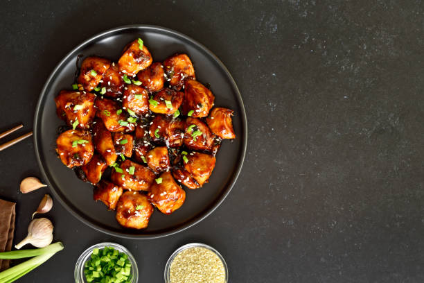 istock Teriyaki chicken on plate over black stone background 1323040192