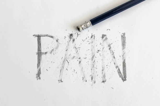Erasing pain. Pain written on white paper with a pencil, erased with an eraser. Symbolic for overcoming pain or treating pain. Erasing pain. Pain written on white paper with a pencil, erased with an eraser. Symbolic for overcoming pain or treating pain. chronic illness stock pictures, royalty-free photos & images