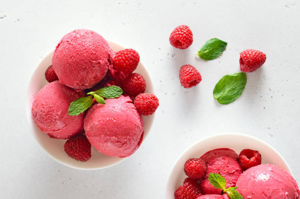 istock Raspberry ice cream scoop with fresh raspberries in white bowl 1323042037