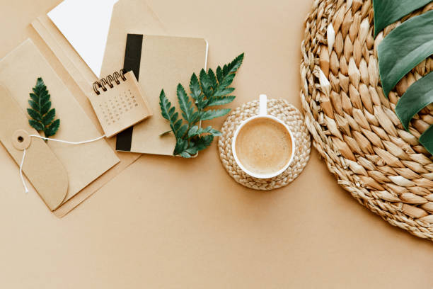 istock Flat lay with coffee cup, calendar, green leaves on brown background. Freelancer workspace, todo list, home office desk, planning concept 1323051981