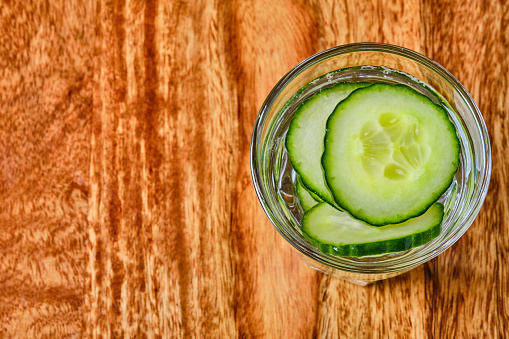 Refreshing water with cucumber in glass top view with copy space