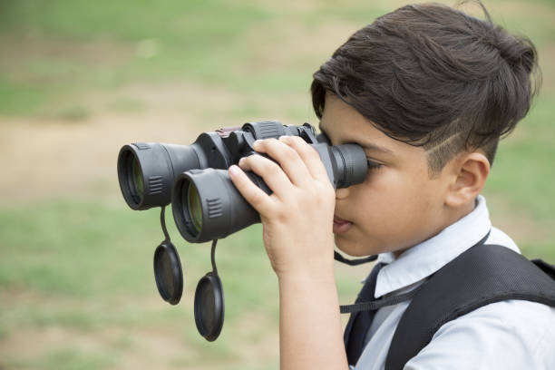 istock little boy looking through binoculars in a school uniform:- stock photo 1323055206