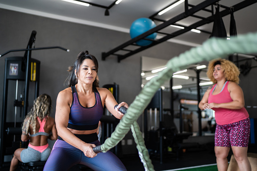 Mature woman working out with battle ropes at the gym