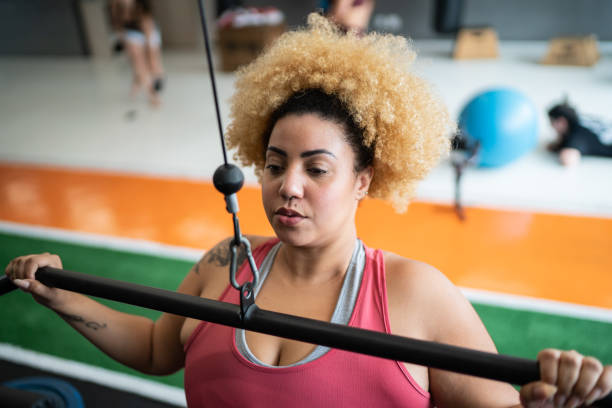 istock Young woman pulling weight machine at the gym 1323057758