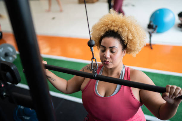 istock Young woman pulling weight machine at the gym 1323057823
