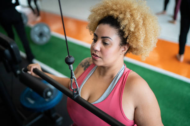 istock Young woman pulling weight machine at the gym 1323057836