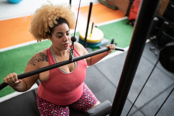Young woman pulling weight machine at the gym
