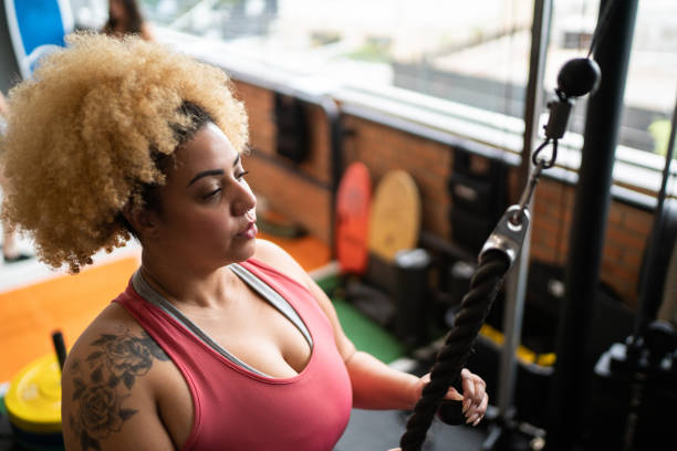 istock Young woman pulling weight machine at the gym 1323057963
