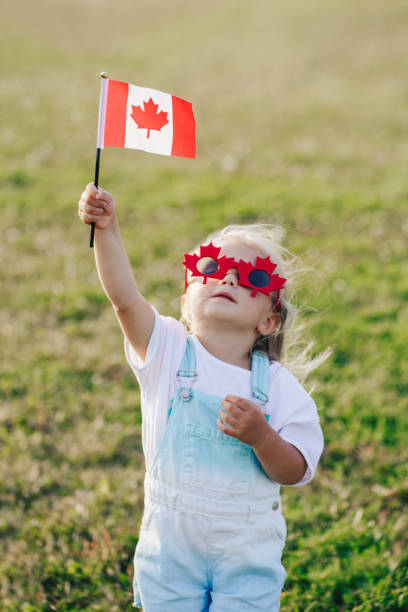 Happy Canada Day. Little Caucasian toddler girl in funny maple leaf sunglasses waving Canadian flag. Kid child citizen celebrating Canada Day outdoor on 1st of July Happy Canada Day. Little Caucasian toddler girl in funny maple leaf sunglasses waving Canadian flag. Kid child citizen celebrating Canada Day outdoor on 1st of July. canada day photos stock pictures, royalty-free photos & images
