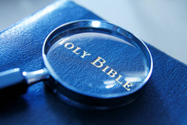 A magnifying glass rests on top of a copy of an old bible. Photographed with a very shallow depth of field.