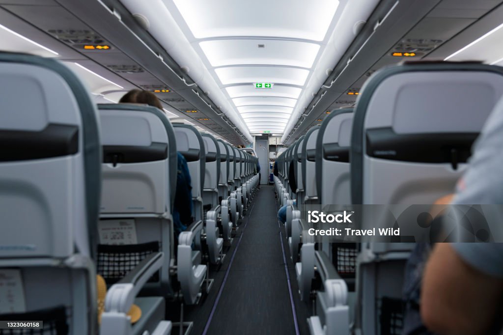 (Selective focus) View of an aircraft cabin with passengers ready for departure. Night flying, concept of travel during the Covid-19, Coronavirus pandemic. Cabin Crew Stock Photo