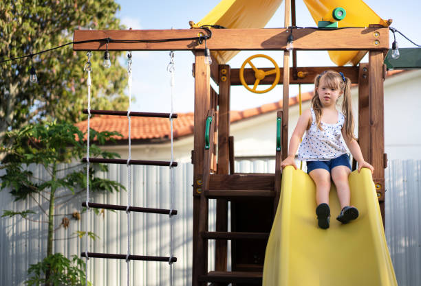 裏庭の滑り台の上に座っている小さな女の子 - swing child swinging front or back yard ストックフォトと画像